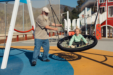 A joyful interaction between a grandparent and grandchild as the grandfather pushes the grandchild...