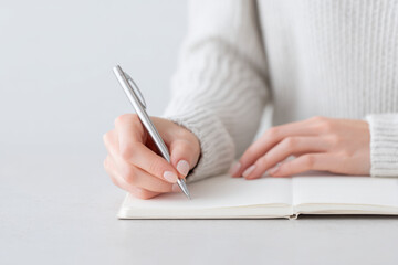 minimalist scene featuring person writing in diary with their left hand on ultrabright clean background