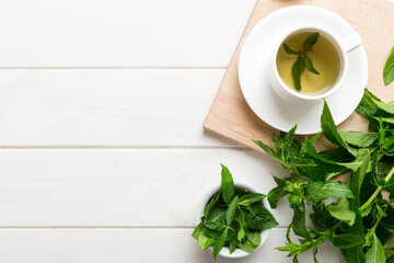 Cup of mint tea on table background. Green tea with fresh mint top view with copy space