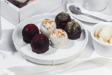 Handmade round chocolate candies on a white plate. Chocolates without sugar. Healthy dessert