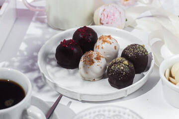 Handmade round chocolate candies on a white plate. Chocolates without sugar. Healthy dessert