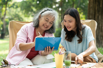 A senior mother and her daughter spend quality time together outdoors, sharing a tender moment filled with love and care. Their strong family bond reflects warmth and togetherness in every embrace