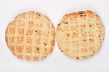 Two round flatbreads with distinct grid patterns and varied browning are arranged on a white background