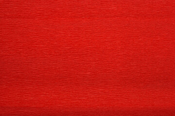 A detailed close-up shot captures the textured surface of a vibrant red crepe paper, showing its...