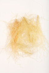 Overhead shot displays a small pile of light brown and yellow corn silk threads on a plain white background