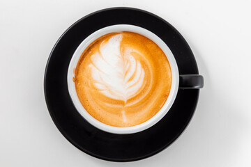 Top View of Fresh Cappuccino with Leaf Latte Art in Black Cup on White Table. Cozy Morning Coffee.  Cafe Beverage, Coffee Break