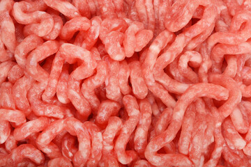 Detailed close-up shot captures the texture of raw, light pink ground meat, showing its individual...