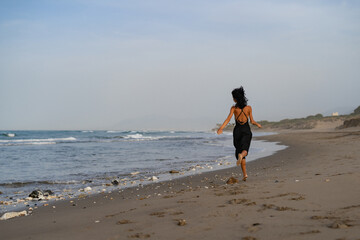 Brunette Woman in Black Dress Running on the Beach