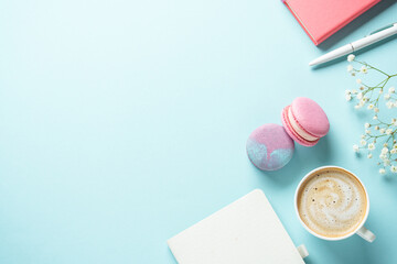 Cup of coffee, macaroon and flower on blue background.