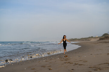 Brunette Woman in Black Dress Running on the Beach