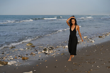 Brunette Woman in Black Dress Walking on the Shoreline