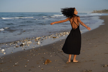 Brunette Woman in Black Dress Walking Along the Beach
