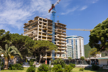 High-rise building under construction with crane and modern urban backdrop. Residential development...