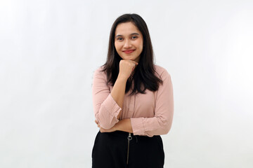 Young confident Asian woman standing on white background, folded hands and holding chin, smiling looking at camera, wearing shirt.