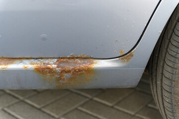 Close-up of rusty car sill with corrosion damage.