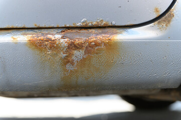 Close-up of rusty car sill with corrosion damage.