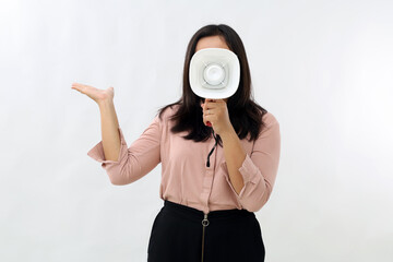 Fototapeta premium Young woman showing or presenting something on the side, giving announcement or information using megaphone, covering face, standing isolated on white background.