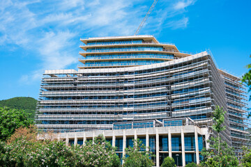 Modern glass building under construction with full scaffolding. Urban development, contemporary...