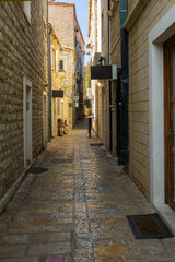 Obraz premium Narrow historic alley with stone buildings in Mediterranean old town. Cultural heritage, summer tourism, and urban charm