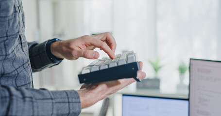 Closeup young adult male freelance developer typing write prompt AI bot app program nomad terminal with coding at office. Artificial intelligence dashboard, robotics, user interface, machine learning.