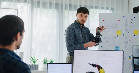 Team adult male engineer develop present AI robotics hand project at tech workspace. Artificial intelligence, collaboration support prototype development, robotic, debugging, machine learn, training.