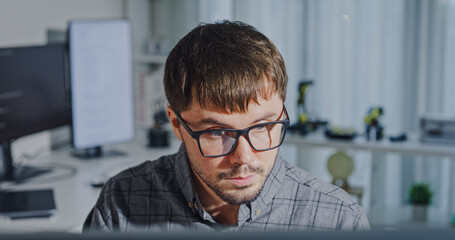 Closeup young adult male freelance developer typing write prompt AI bot app program nomad terminal with coding at office. Artificial intelligence dashboard, robotics, user interface, machine learning.