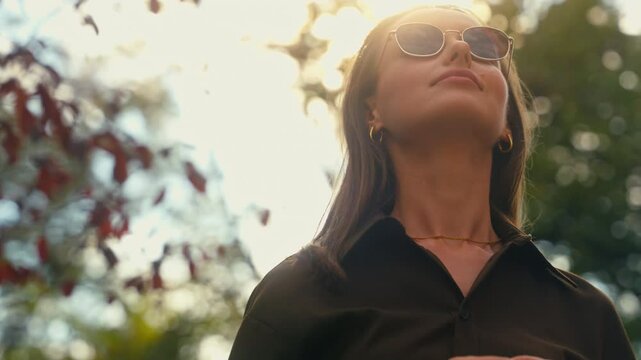 Stylish happy Caucasian woman put on dark glasses wearing sunglasses businesswoman female girl at street autumn city looking around enjoying weather healthy cheerful smiling outdoors fashion style