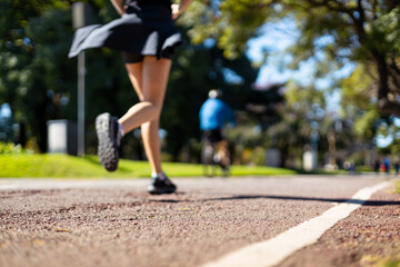 A blurred shot of a young woman's legs running in the park on a sunny day, ideal for a background