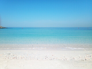 Peaceful view of the sea along the coast of Sharjah, United Arab Emirates. The image captures the calm Arabian Gulf waters under a clear sky, with gentle waves lapping against the shore.
