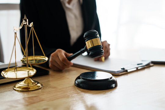 A professional lawyer advises a client in a legal office, reviewing contracts and justice symbols like a gavel and legal books