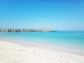 Peaceful view of the sea along the coast of Sharjah, United Arab Emirates. The image captures the calm Arabian Gulf waters under a clear sky, with gentle waves lapping against the shore.
