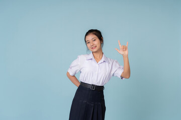 The high school girl is posing cheerfully with school supplies in hand, styled as a model for an advertising campaign promoting effective tutoring in a blue background in studio.