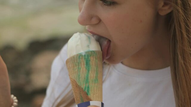 Teenager girl savoring creamy ice cream cone, radiating joy with bright smile during sunny summer day, capturing blissful moment of sweet indulgence.Travel, tourism, food and drink.