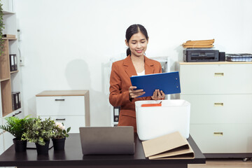 Asian woman holding big boxes of belongings to move to new office with big background. Young woman...