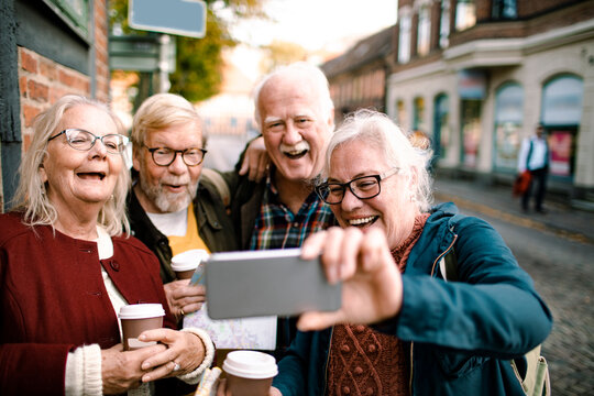 Senior friends sightseeing and looking at phone while exploring city