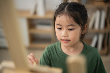 Young girl focused on painting at easel, creative expression in art studio, colorful brush strokes,...