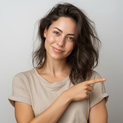 An attractive woman smiling and pointing, exuding confidence and positivity in a neutral background.