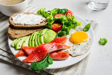 Healthy breakfast - fried egg, salmon, avocado and green salad