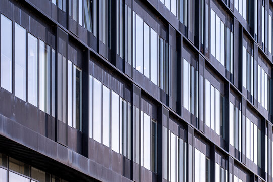 Contemporary building facade with dark frames and reflective windows, architectural rhythm and cool tones with perspective emphasizing geometry and depth
