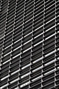 Repetitive metal mesh pattern in architectural facade, modern texture and high contrast composition ideal for design and structure based visual narratives