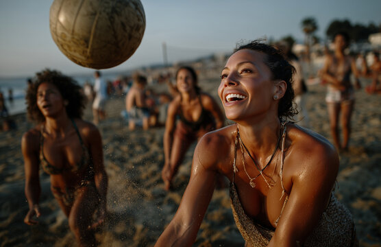 Happy friends playing beach volleyball during sunset