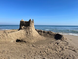 Majestic Sandcastle on a Sunny Beach Under a Clear Blue Sky