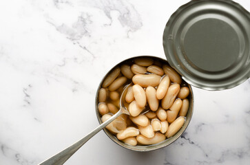 Top view of a spoon in a can of white beans with copy space. Food preservation concept. 