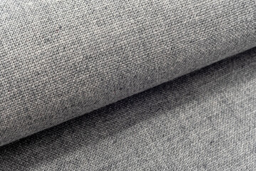 A twisted piece of grey fabric. A roll of blue fabric. Textile. Folds.