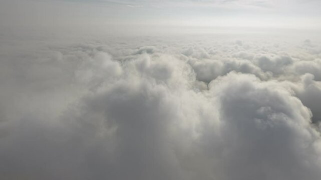 A stunning aerial view capturing the serene beauty of clouds from above. Soft, billowing formations stretch across the sky, bathed in golden sunlight.