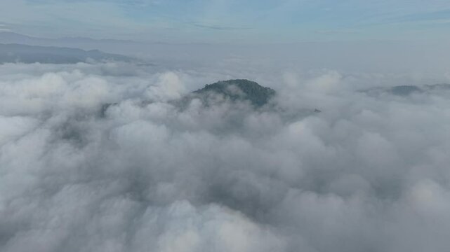 A stunning aerial view capture the serene beauty of clouds from above. Soft, billowing formations stretch across the sky, bathed in golden sunlight and casting gentle shadows over the landscape below.