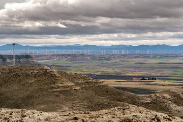 Elevated view of dry hills and distant city skyline in Zaragoza, Spain, natural terrain, transition zone and energy potential in Mediterranean rural landscape