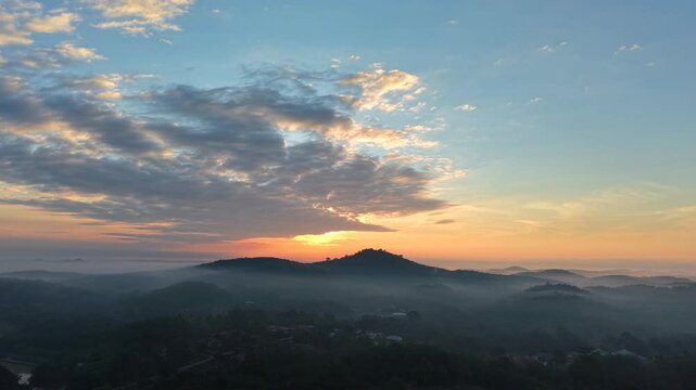 Dramatic morning sunrise over an Asian oil palm plantation. Golden light pierces through low mist, casting long shadows across neat rows of palm trees and creating a warm, cinematic landscape.