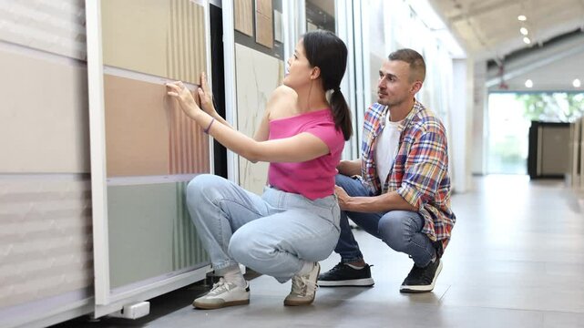 Young married couple chooses floor tiles for their home together. High quality 4k footage