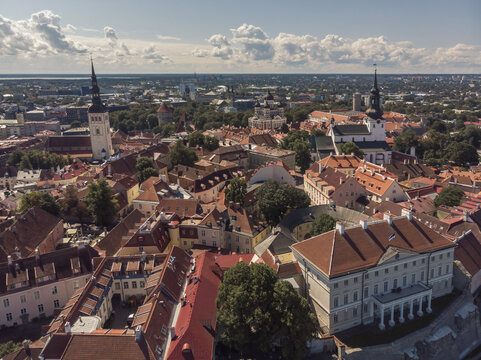 Aerial view of a historic European town with red-tiled roofs, medieval spires, and a blend of classical architecture. A rich blend of culture and history captured from above.